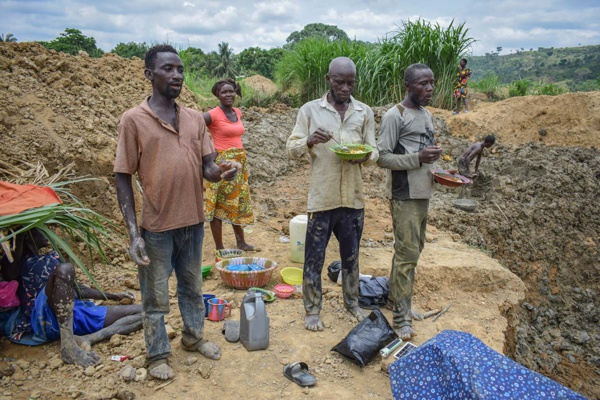 Pause déjeuner. Des creuseurs reçoivent un bol de riz avec du poisson et des feuilles de manioc. Pour beaucoup, c'est leur seul repas de la journée. (Photo : Josef Skrdlik/OCCRP)