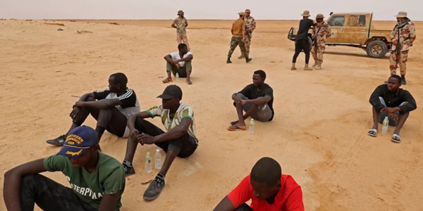 des migrants dans le désert du Sahara sous la surveillance de policiers d'Etat des migrants dans le désert du Sahara sous la surveillance de policiers d'Etat
