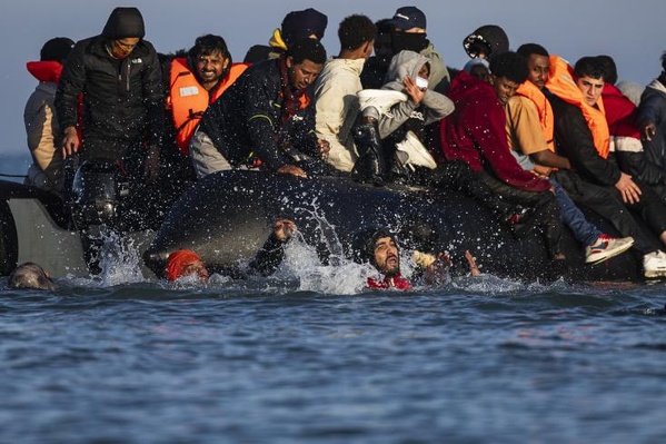 Photo et légende AFP - Des migrants tentent d'embarquer sur un bateau de passeurs afin de traverser la Manche au large de Gravelines (nord de la France) le 27 septembre 2025