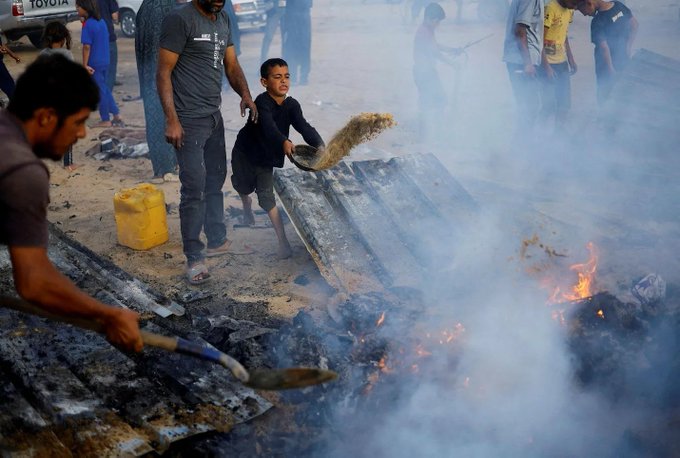 Rafah, 26 mai 2024. Un enfant palestinien tente d'éteindre le feu après les missiles d'Israël sur un camp de réfugiés de l'ONU.